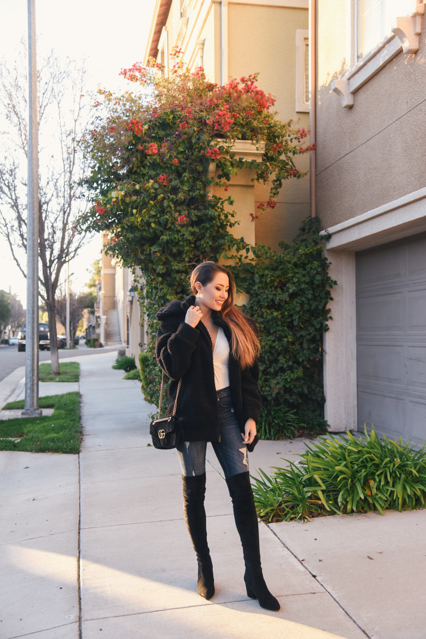 brunette wearing faux fur coat over the knee boots winter out