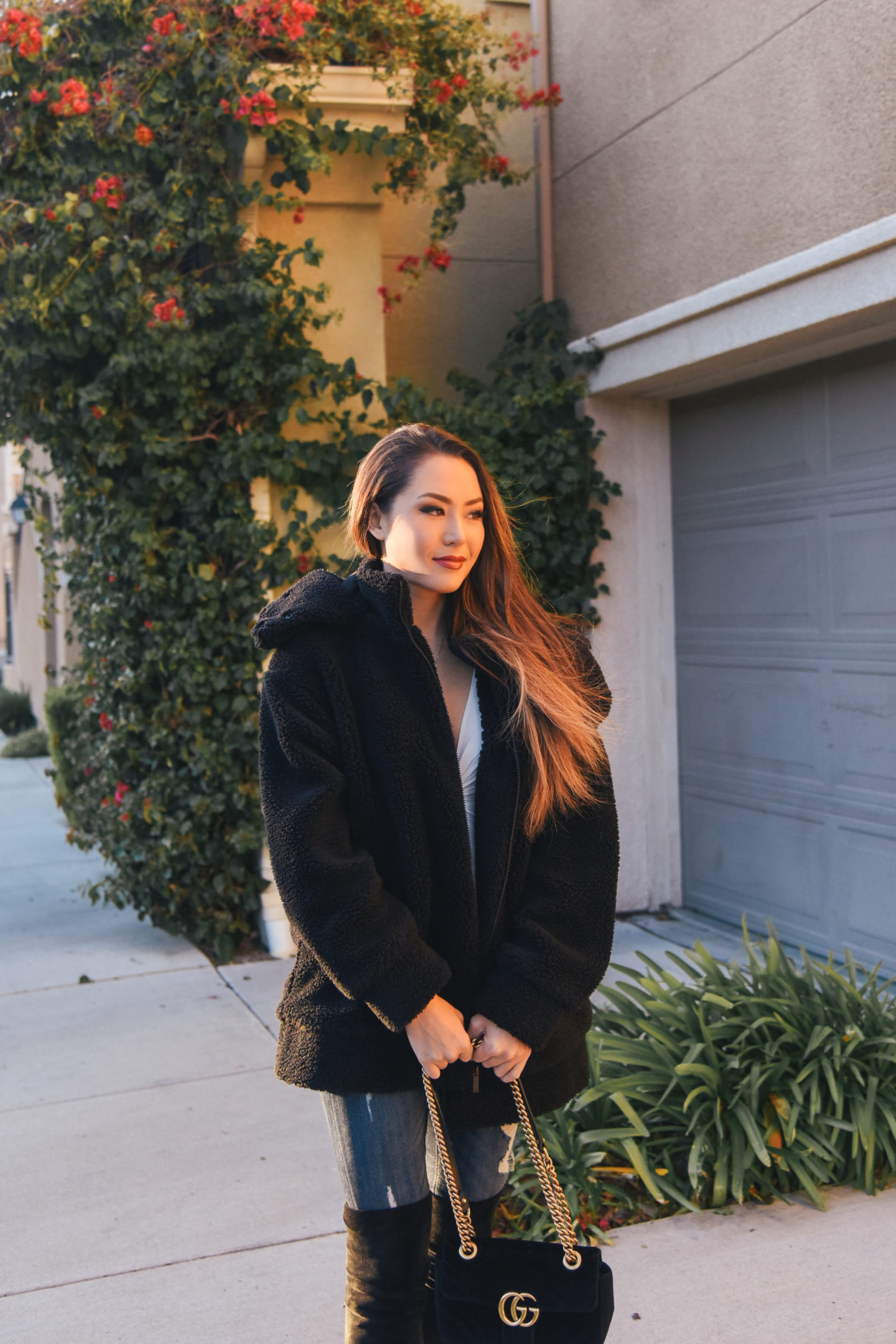 brunette wearing faux fur coat over the knee boots winter out